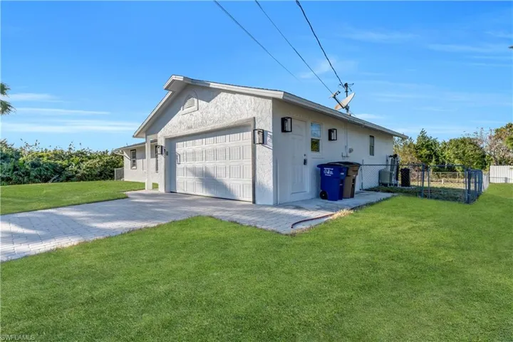 View of property exterior with fence, a lawn, stucco siding, decorative driveway, and a garage