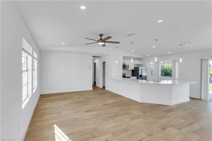 Unfurnished living room with visible vents, a sink, recessed lighting, light wood finished floors, and lofted ceiling