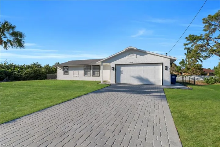 Ranch-style house with fence, an attached garage, stucco siding, a front lawn, and decorative driveway