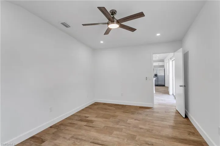 Spare room featuring light wood-type flooring, visible vents, recessed lighting, baseboards, and ceiling fan