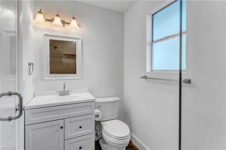 Bathroom with vanity, toilet, a shower, and baseboards