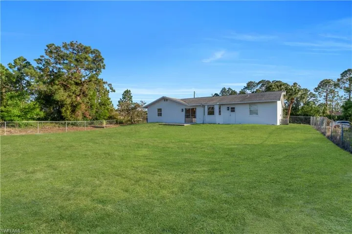 Back of property featuring stucco siding, cooling unit, a lawn, and a fenced backyard