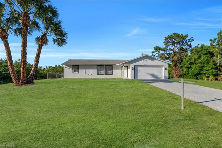 Ranch-style home with a front lawn, a garage, driveway, and stucco siding