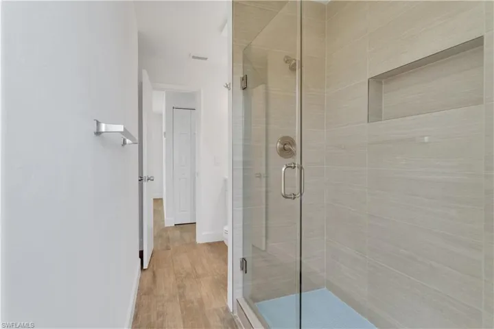 Bathroom featuring wood finished floors, a stall shower, and baseboards