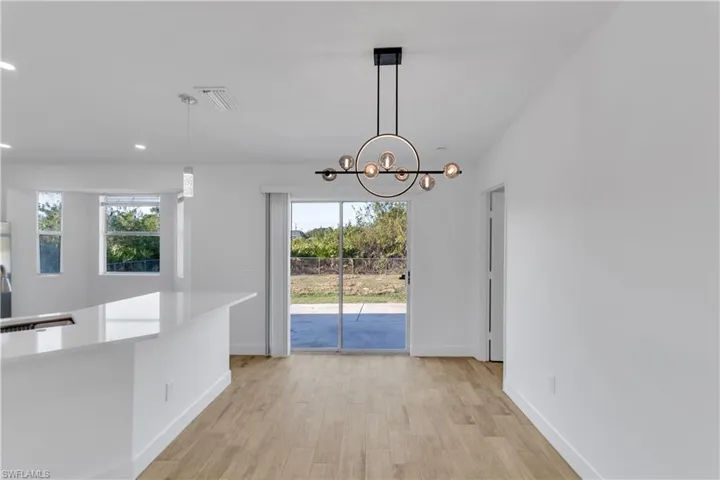 Unfurnished dining area featuring visible vents, an inviting chandelier, baseboards, and light wood-style floors
