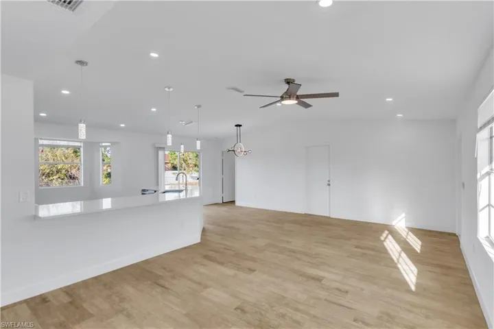 Unfurnished living room featuring light wood finished floors, baseboards, ceiling fan, recessed lighting, and a sink