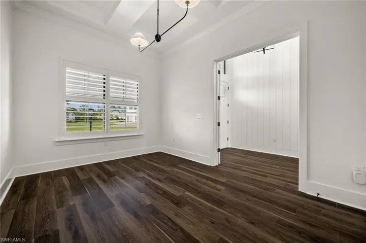 Unfurnished dining area with ornamental molding, dark wood-style floors, baseboards, and a chandelier