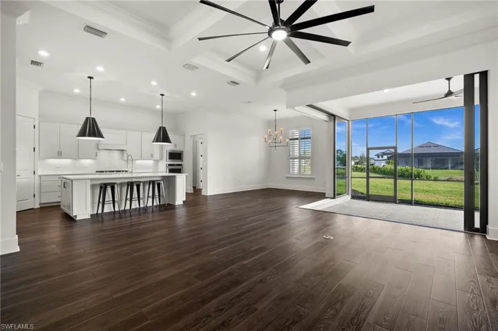 Unfurnished living room featuring ceiling fan, coffered ceiling, a chandelier, dark wood-type flooring, and recessed lighting