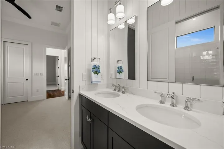 Bathroom featuring ornamental molding, double vanity, and a tile shower