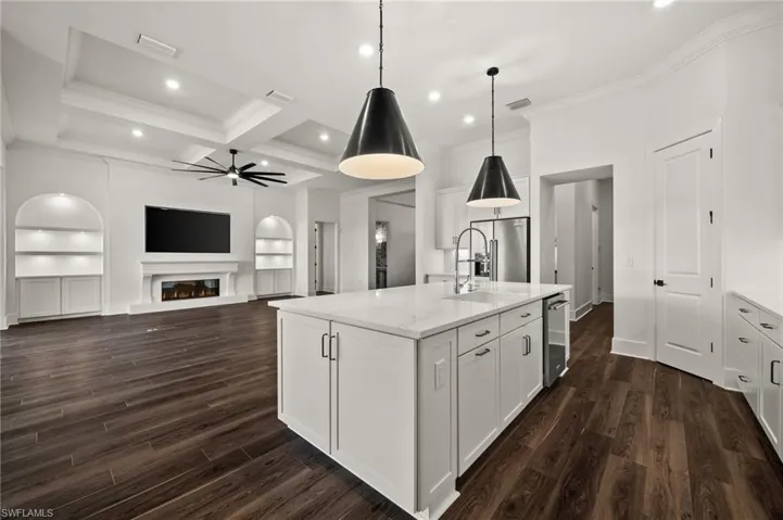 Kitchen with a sink, a ceiling fan, ornamental molding, white cabinetry, and dark wood-type flooring