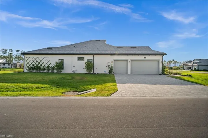 View of front of house with an attached garage, decorative driveway, a front yard, and stucco siding
