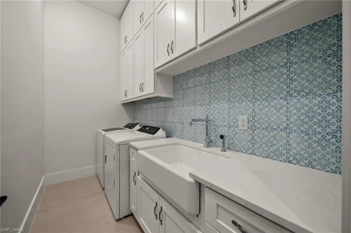 Washroom with independent washer and dryer, cabinet space, baseboards, and light tile patterned floors