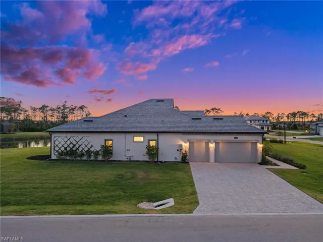 View of front of property with an attached garage, a yard, driveway, and a water view
