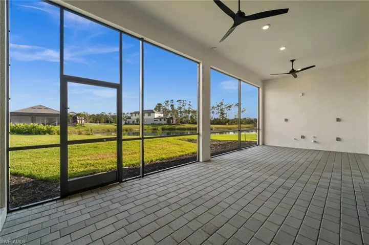 Unfurnished sunroom featuring a ceiling fan and a water view