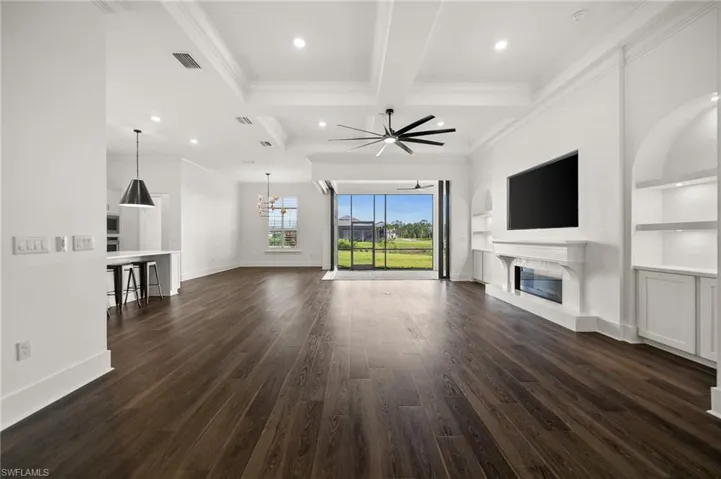 Unfurnished living room with a high end fireplace, ceiling fan, ornamental molding, coffered ceiling, and dark wood-style floors
