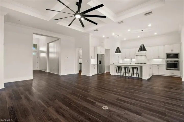 Unfurnished living room with coffered ceiling, ceiling fan, dark wood-style flooring, recessed lighting, and ornamental molding
