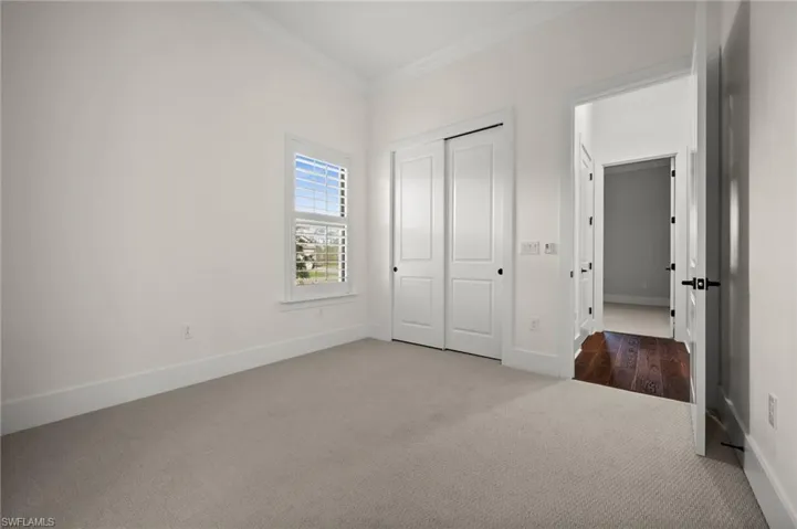 Unfurnished bedroom featuring carpet, crown molding, baseboards, and a closet