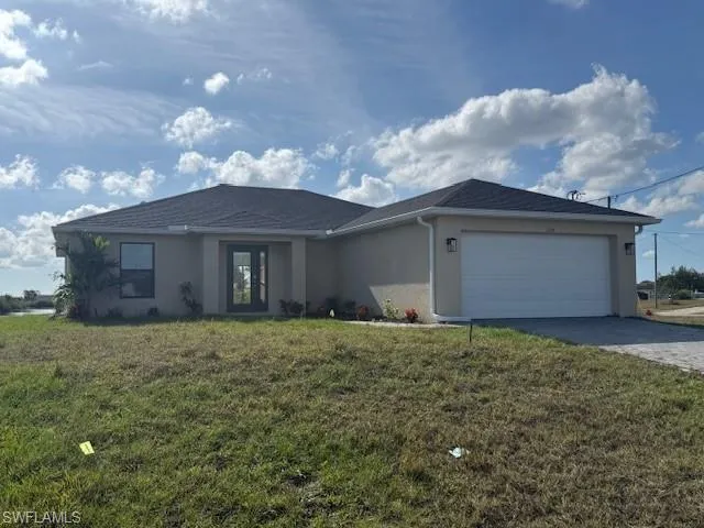 Single story home with stucco siding, a front yard, a garage, and decorative driveway