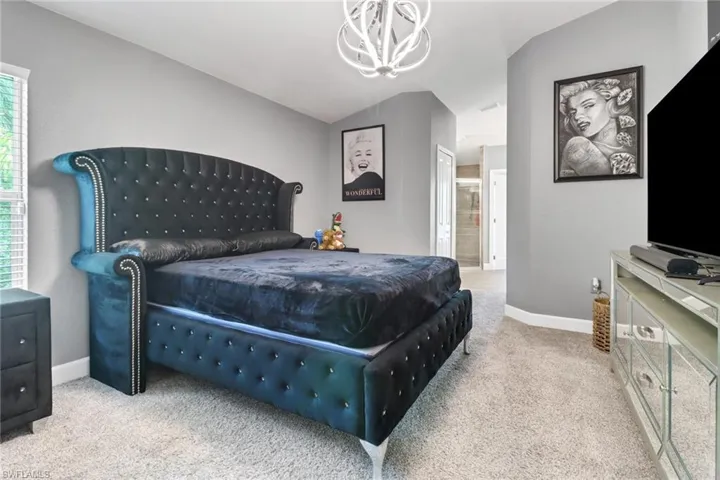 Master Bedroom with light carpet, vaulted ceiling, an inviting chandelier, and ensuite bath