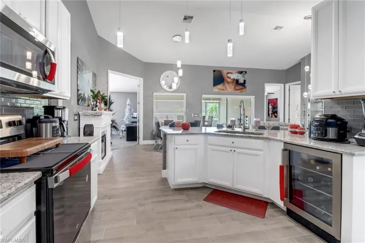 Kitchen with beverage cooler, white cabinets, appliances with stainless steel finishes, and sink