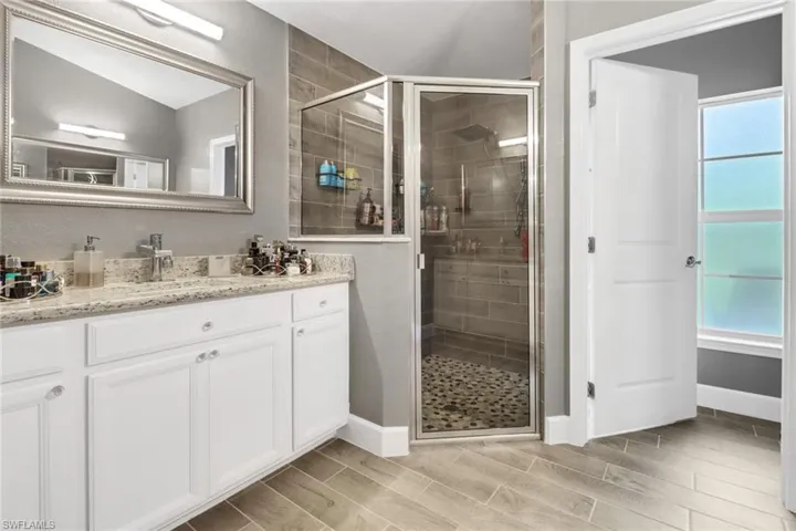 Master bathroom with separate sink area. Featuring separate vanity's, vaulted ceiling, and an enclosed shower.