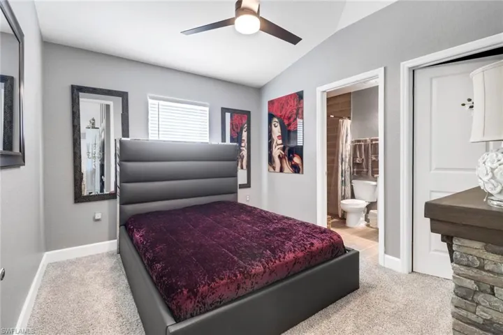 Guest bedroom 1. Carpeted bedroom with ceiling fan, vaulted ceiling, and ensuite bathroom