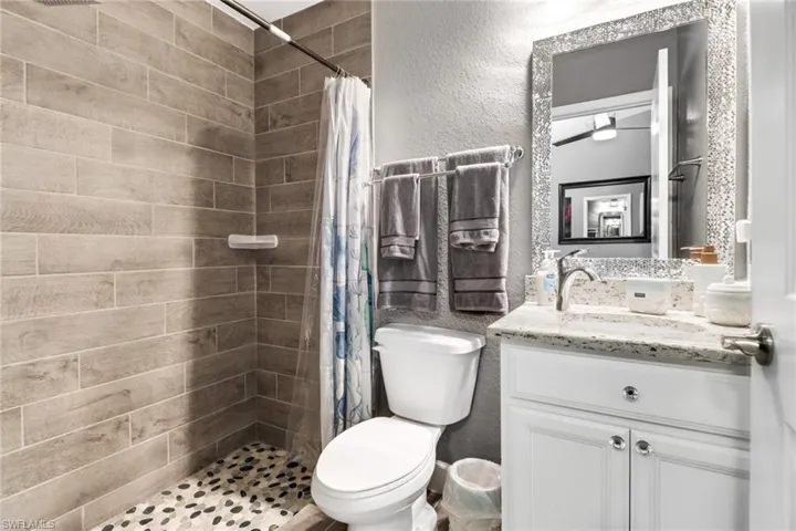 Bathroom featuring curtained shower, vanity, and toilet