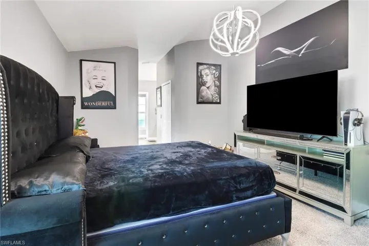 Master Bedroom featuring an inviting chandelier, lofted ceiling, and carpet