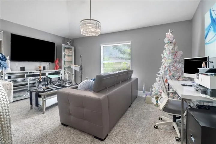 Den/theater room featuring chandelier and light colored carpet.