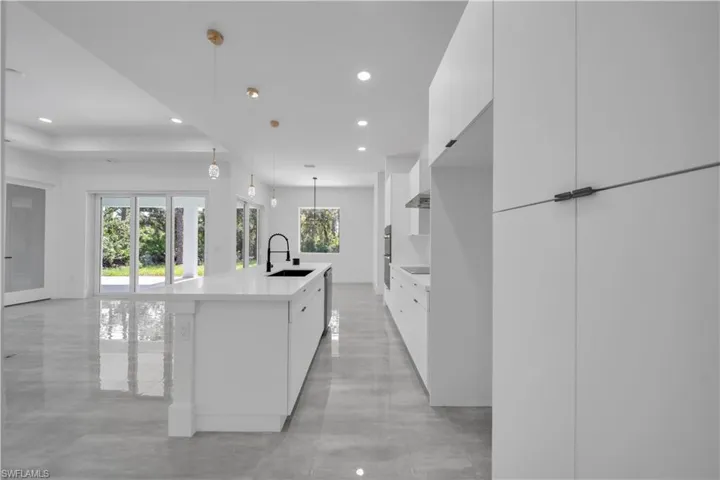 Kitchen featuring hanging light fixtures, white cabinetry, a kitchen island with sink, a kitchen breakfast bar, and recessed lighting