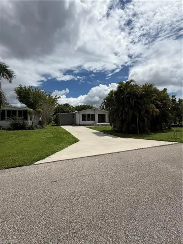 View of front of property featuring driveway, a front yard, and a sunroom