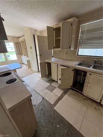 Kitchen featuring light countertops, decorative backsplash, a textured ceiling, open shelves, and light tile patterned floors