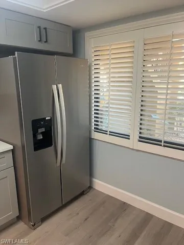 Kitchen featuring light wood-style floors, stainless steel fridge with ice dispenser, baseboards, and plenty of natural light