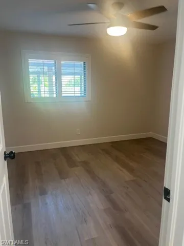 Unfurnished room with wood finished floors, ceiling fan, and baseboards