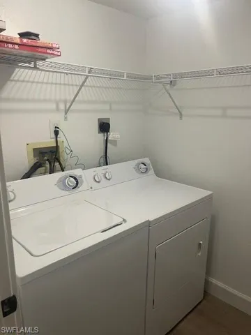 Washroom with separate washer and dryer, baseboards, and dark wood-style floors