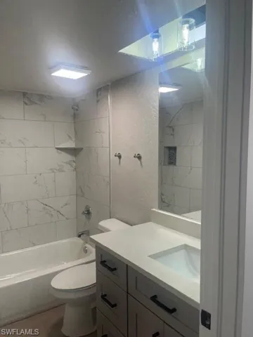 Full bath with toilet, wood finished floors, vanity, and shower / bathtub combination