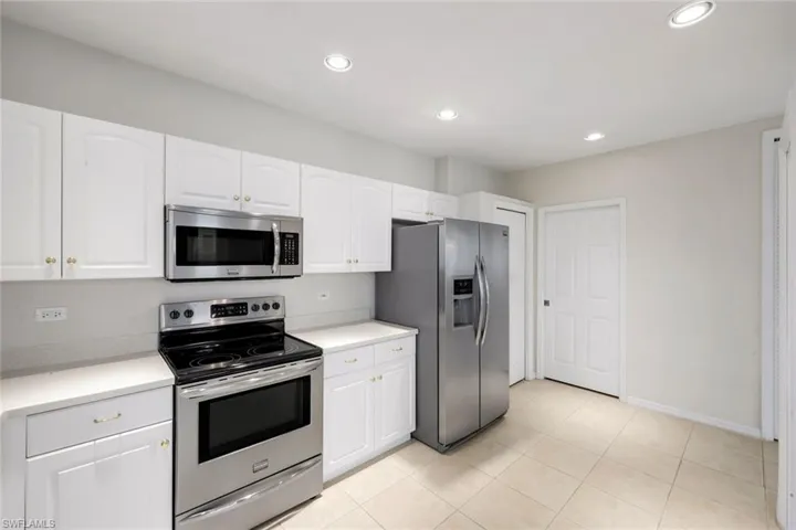 Kitchen with stainless steel appliances, light countertops, white cabinets, recessed lighting, and light tile patterned floors