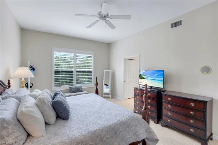 Bedroom featuring a closet, light colored carpet, and ceiling fan
