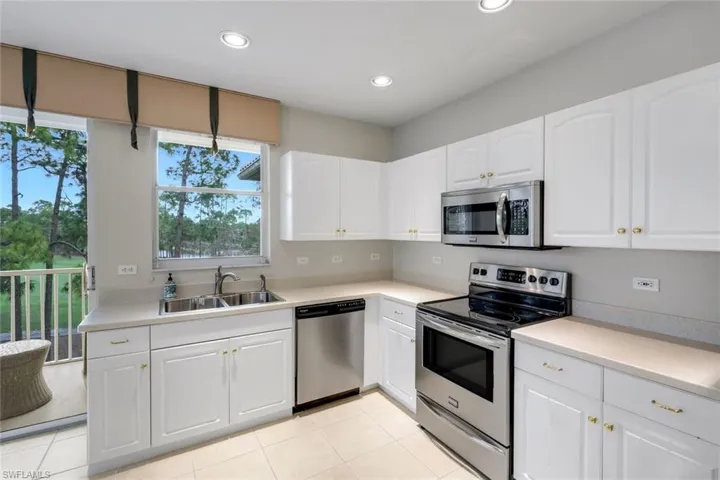 Kitchen featuring stainless steel appliances, light countertops, white cabinets, and recessed lighting