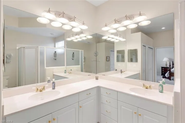 Bathroom featuring double vanity, a shower stall, and a closet