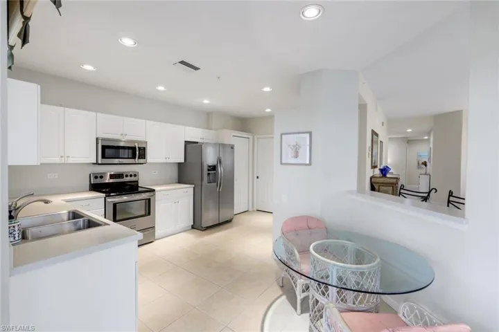 Kitchen with stainless steel appliances, white cabinetry, light countertops, and recessed lighting
