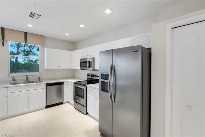 Kitchen with stainless steel appliances, white cabinets, light countertops, recessed lighting, and light tile patterned flooring