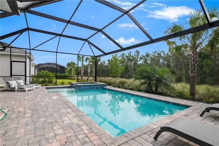 View of swimming pool with a patio area, a pool with connected hot tub, and a lanai