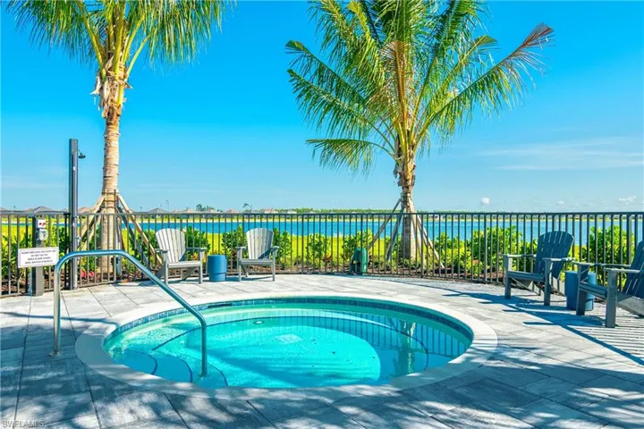 View of swimming pool with a water view, a patio, and a hot tub