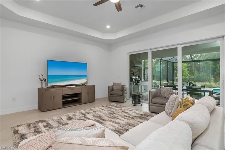 Living area with ceiling fan, a sunroom, a tray ceiling, and recessed lighting