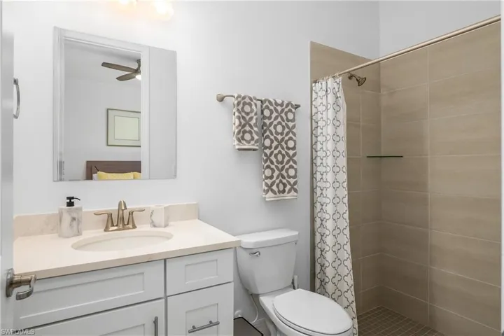 Full bath with vanity, a tile shower, and a ceiling fan