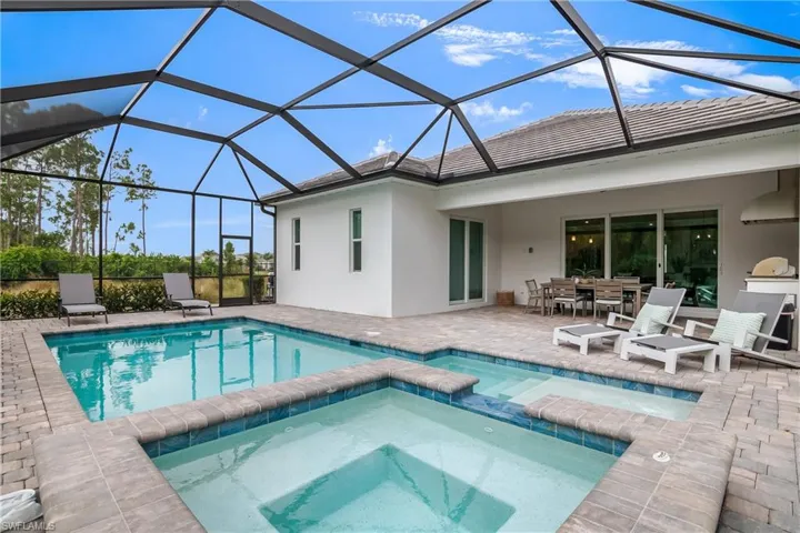 View of pool with a patio, a pool with connected hot tub, outdoor dining space, and a lanai