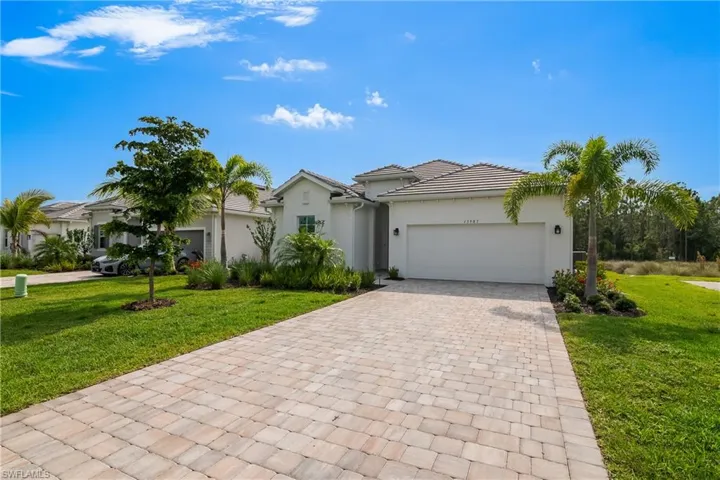 Ranch-style house with stucco siding, a garage, decorative driveway, and a front yard