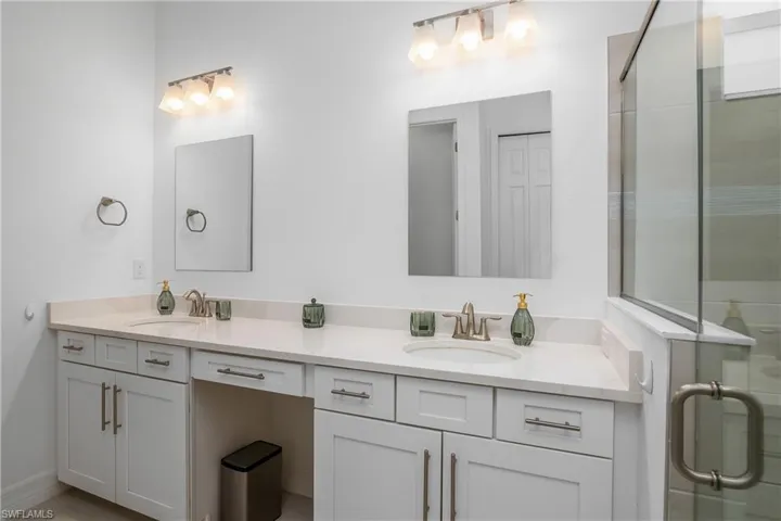Full bath with double vanity and a tile shower