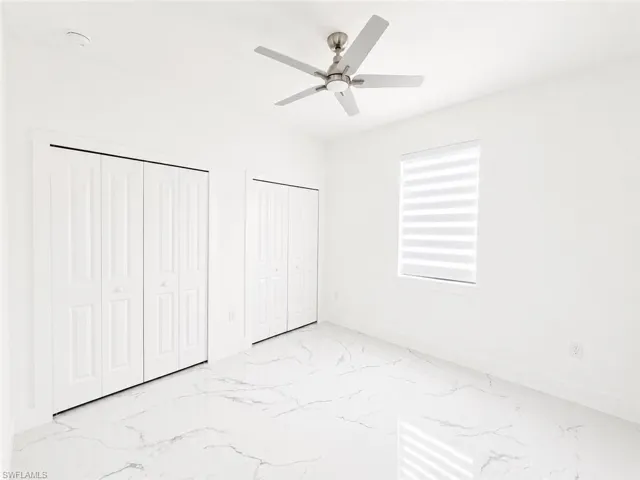 Spacious room featuring large format tile flooring, a modern ceiling fan, and two bifold closet doors